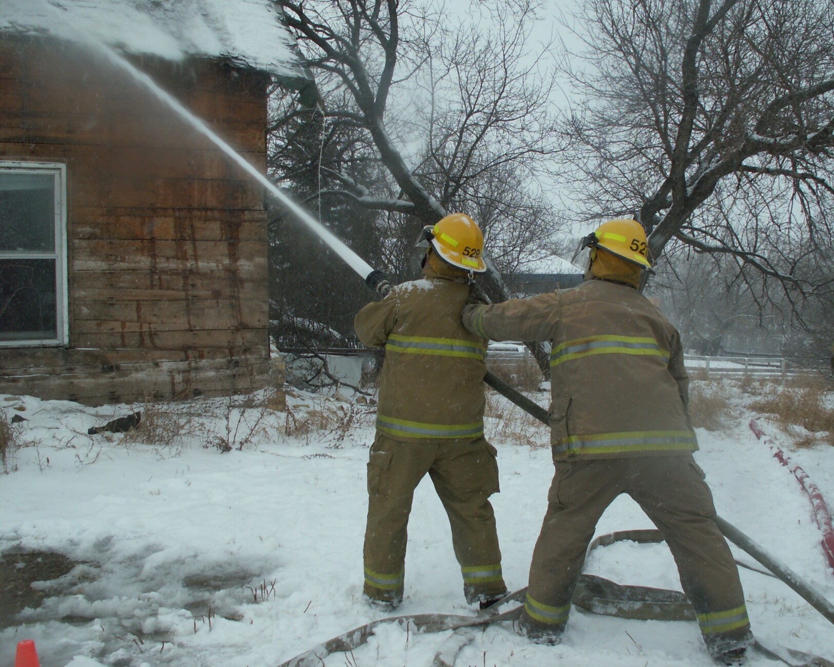 firefighters using water on house in winter