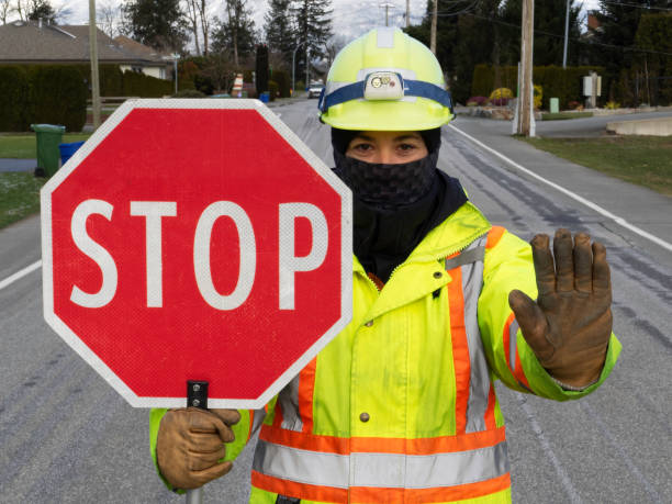 Female traffic control flagger at work holding a stop sign