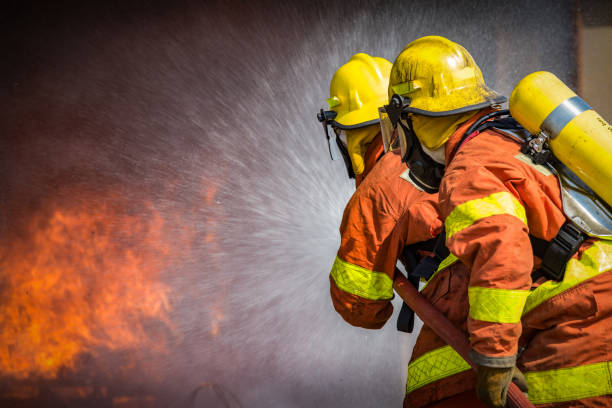 2 firefighters spraying high pressure water to fire with copy space