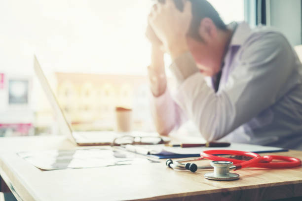 Stethoscope and doctor sitting with laptop stress headache about work in hospital
